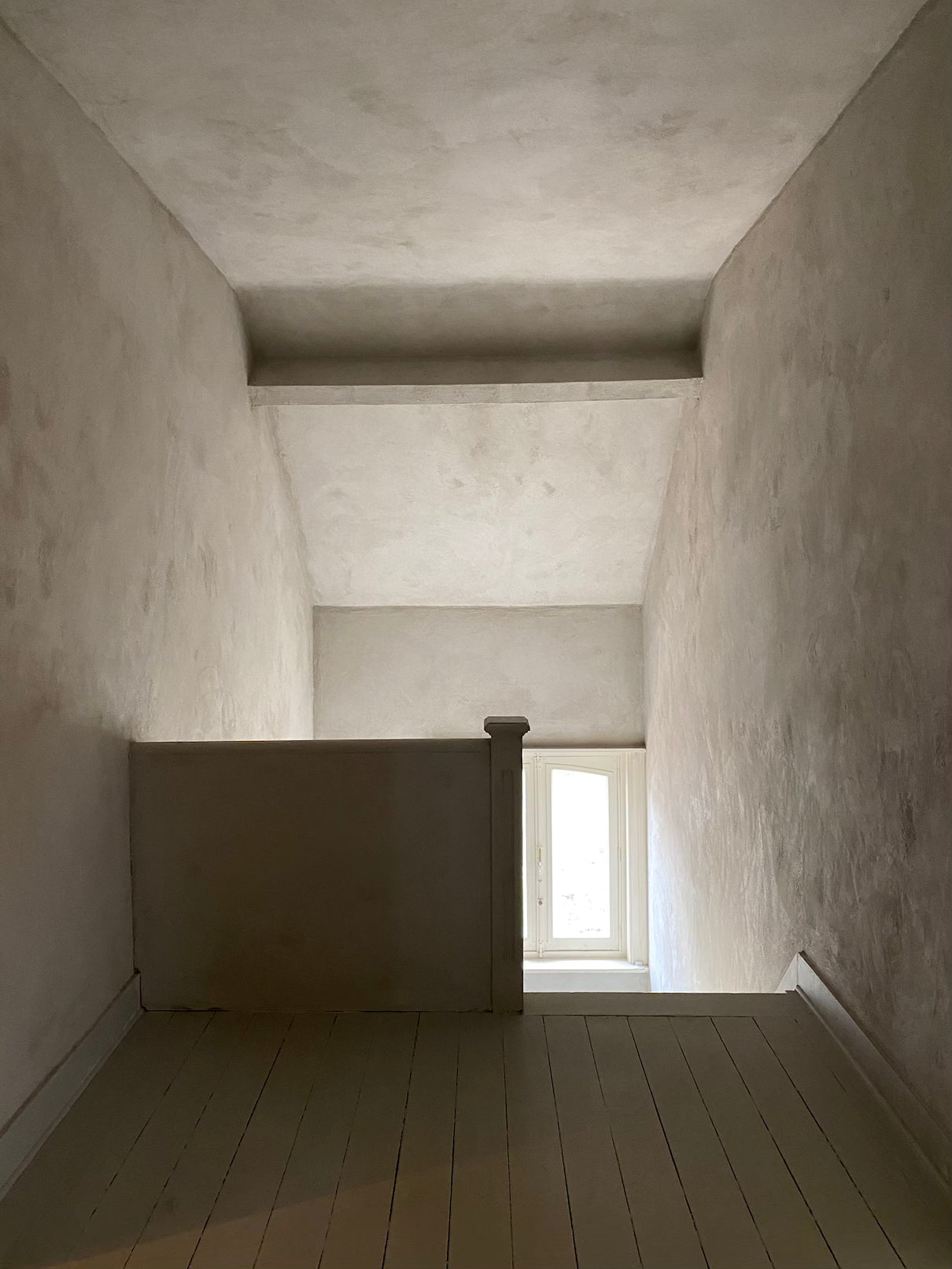 Narrow hallway with a window at the end in a minimalistic room.